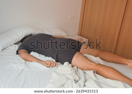 Man sleeping face down in bed, struggling with a hangover after a night of partying, showcasing aftermath of wild night's excessive alcohol consumption