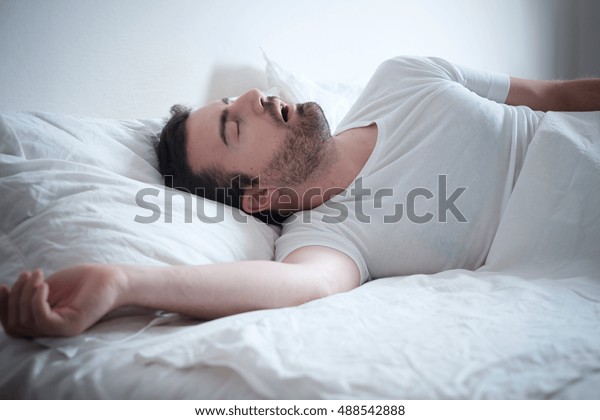Man sleeping in\
his bed and snoring loudly