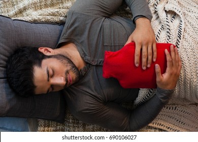 Man sleeping with hot water bag at home - Powered by Shutterstock