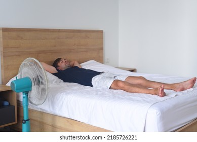 Man Sleeping On A Bed With Fan 