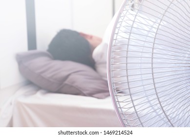 A Man Sleeping On The Bed And Turn On The Fan Over The Head Risks Of Respiratory System.Health And Medical Care Concepts