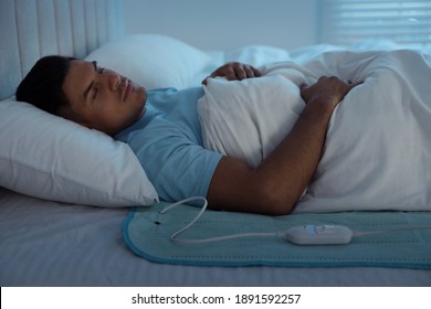 Man Sleeping On Electric Heating Pad In Bed At Night