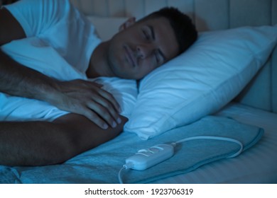 Man Sleeping On Electric Heating Pad In Bed At Night