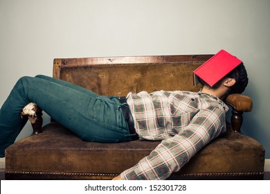 Man Sleeping On Old Sofa With Book Covering His Face