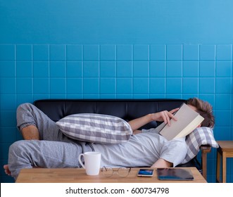 Man sleeping on old sofa with book covering his face because reading boook with preparing exam, education concept - Powered by Shutterstock