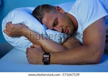 Man Sleeping With Smart Watch In His Hand Showing Heartbeat Rate