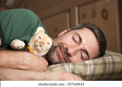 A Man Sleeping While Cuddling A Toy Tiger.