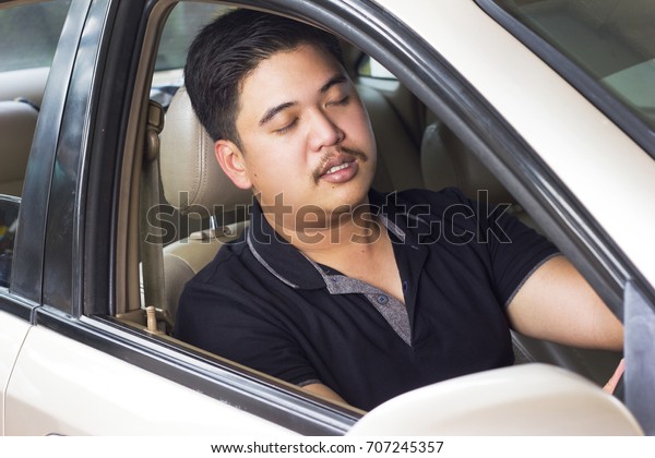 Man Sleepy and\
yawning while driving car.