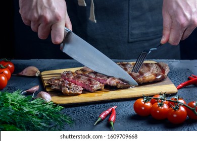 A man slices a steak with a knife and fork. Cropped photo with hands closeup. Fresh medium beef steak. - Powered by Shutterstock