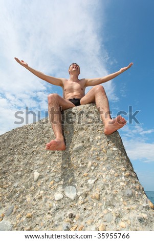 man in slips sits on rock, bottom view