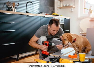 Man With Small Yellow Dog Working On A New Kitchen Installation