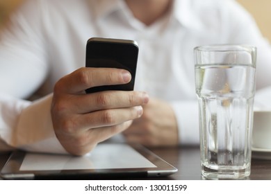 Man With Smart Phone In Hand, Blurred Background, Glass Of Wather