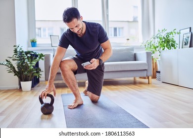 Man With Smartphone Checking Training App Before Home Workout Exercises 