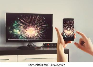 Man With Smartphone Connected To A TV Watching Video At Home. Transfer Video From Phone To TV Screen. Modern Gadgets. Information Transfer Between Devices Over Wifi.