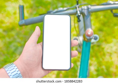 Man With A Smartphone On A Bicycle Workout On Offroad. Mockup. Trendy Photo. Flat Lay Concept: Devices For Everyday Life. Phone With Blank Screen, Copy Space.