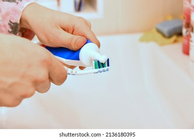 A Man Smears A Toothbrush With Toothpaste.