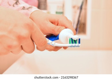 A Man Smears A Toothbrush With Toothpaste.