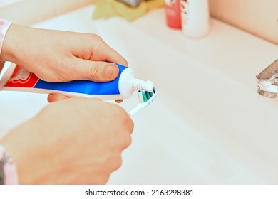 A Man Smears A Toothbrush With Toothpaste.