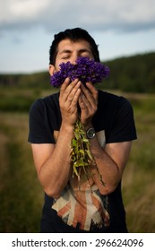 Man Smelling Flowers In A Field