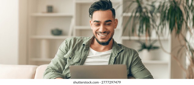 Man Smiles While Using Laptop in Living Room at Home During Daylight Hours