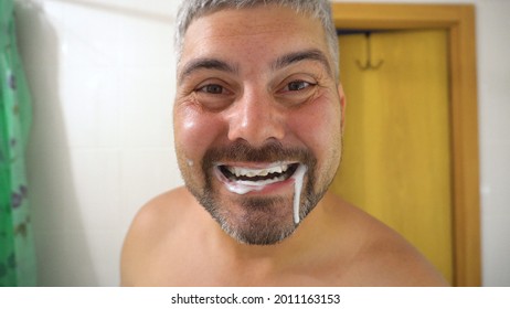 The Man Smiles. White Toothpaste In The Mouth. Bathroom. Beard On The Face. Short Haircut. Tanned Skin. Close-up. Healthy Teeth. Dentistry.