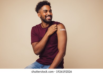 Man smiling after receiving vaccination. Man showing his arm after receiving a vaccine. - Powered by Shutterstock