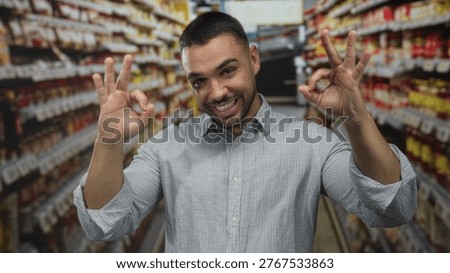 Man smiling broadly while making ok sign with both hands in bright supermarket aisle; approval happiness.