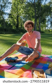 Man smiling at camera while eating banana and cake on a colorful blanket