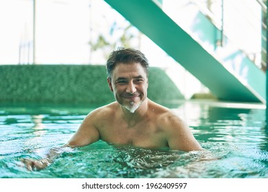 Man smiling, enjoying indoor swimming pool. Concepts of spa, wellness. - Powered by Shutterstock