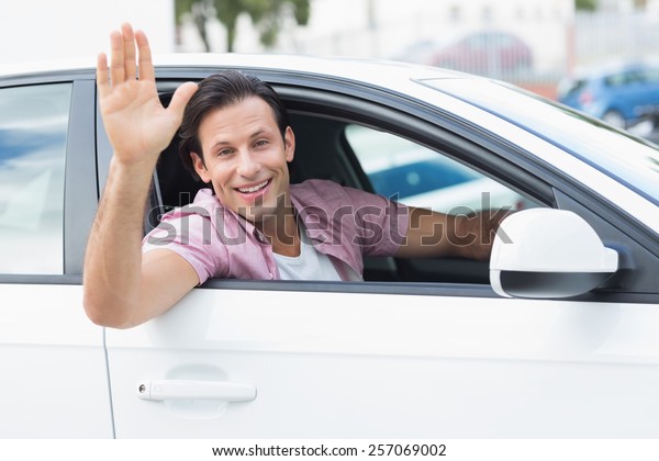 Man smiling and waving in\
his car