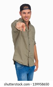 Man Smiling And Wearing Baseball Hat Backwards And Pointing On White Background