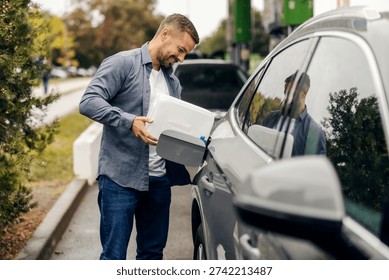 Hombre sonriendo mientras agrega gasolina de un bidón blanco al tanque de combustible de un automóvil gris en una gasolinera al lado de la carretera, abordando una situación inesperada del tanque vacío