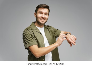 Man smiling while adjusting smartwatch in a neutral studio background during a bright, lively moment