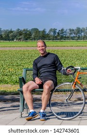 Man smiling while sitting on a bench with his bike