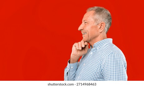 Man Smiling While Thinking Against a Bright Red Background During the Day