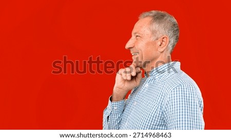 Man Smiling While Thinking Against a Bright Red Background During the Day
