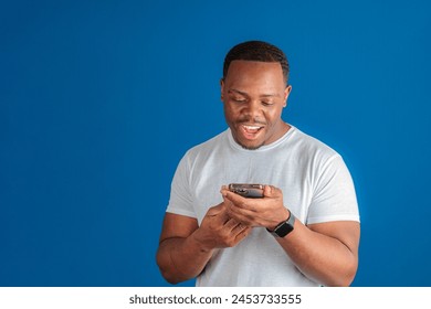 Man smiling while using his smartphone on blue background