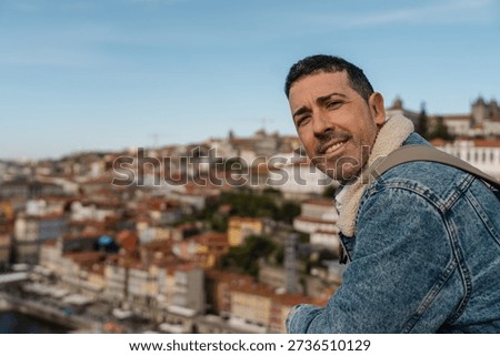Man smiling while wearing a denim jacket overlooking the city of porto, portugal