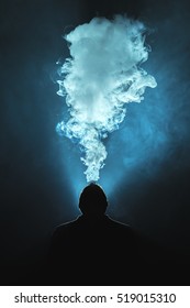 The man smoke an electronic cigarette against the background of the bright light