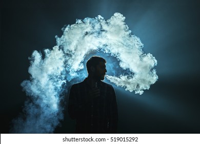 The Man Smoke An Electronic Cigarette On The Dark Background