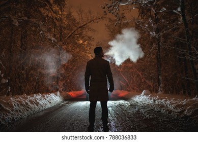 The man smoke on the snowy road in the forest. evening night time - Powered by Shutterstock