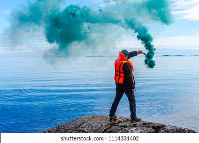 A man with a smoke torch. The rescue. Distress call. The man lights a smoke signal. A man in a life jacket. SOS. signal by smoke. - Shutterstock ID 1114331402