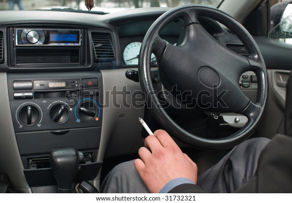 The man smokes in car\
salon.