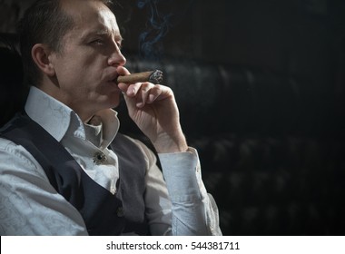 A man smokes a cigar and the smoke released from the mouth