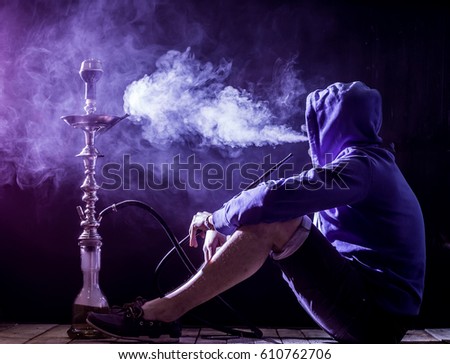 a man smokes a hookah on a black background, holiday concept, beautiful lighting