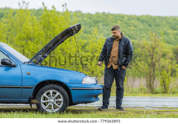 Man smokes near a car on\
the road