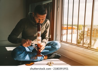 Man Smoking Bong And Inhaling The Smoke At Home. Man Smoking Pot, Medical Marijuana Or Cannabis From A Bong Or Water Pipe