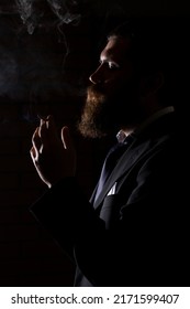 Man smoking cigarette isolated on black. A man smokes cannabis weed, a joint and a lighter in his hands. Smoke on black background. Concepts of medical marijuana use and legalization of the cannabis.