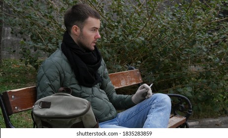 Man Smoking in the morning on a bench. The weather is cold.