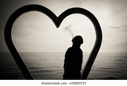 man smoking silhouette on the beach. Love is not satisfied sad concept 
